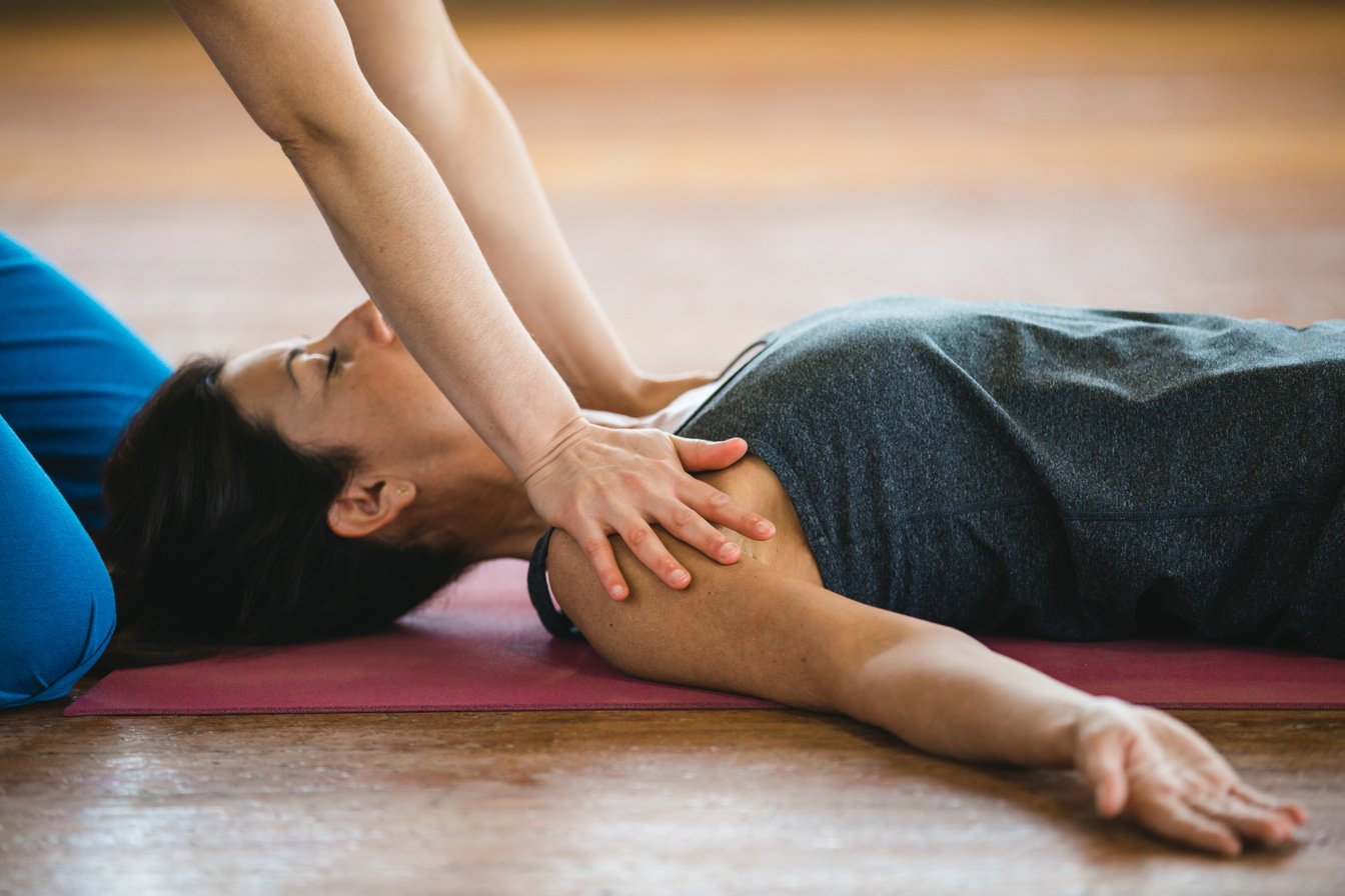 Savasana, Shavasana or Corpse pose and shoulders massage. Women practicing yoga position and massage